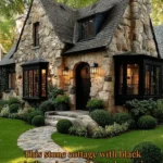 Charming stone cottage with black windows surrounded by lush greenery