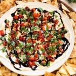 Delicious bruschetta dip served in a bowl with fresh ingredients around it