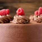 Decadent Chocolate Raspberry Cake garnished with fresh raspberries and chocolate shavings.